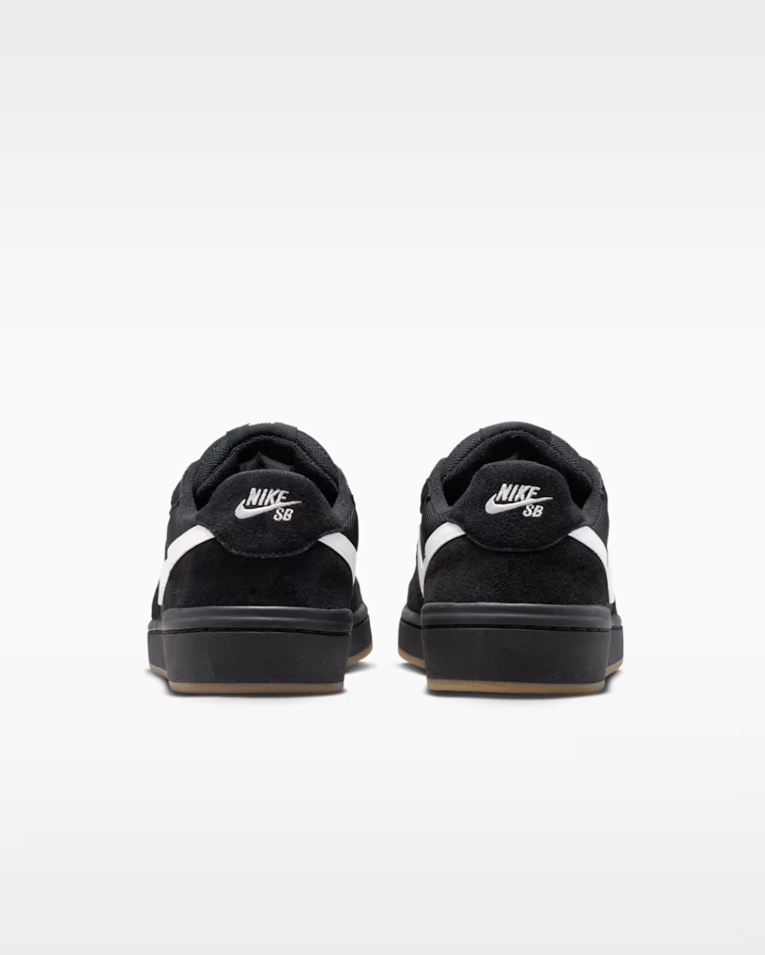 A pair of black Nike SB low-top sneakers shown from the back, featuring white swooshes and white 'Nike SB' branding on the heel, set against a clean white background.