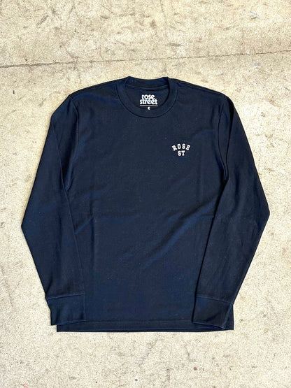 Navy long-sleeve shirt with white text on a beige concrete floor