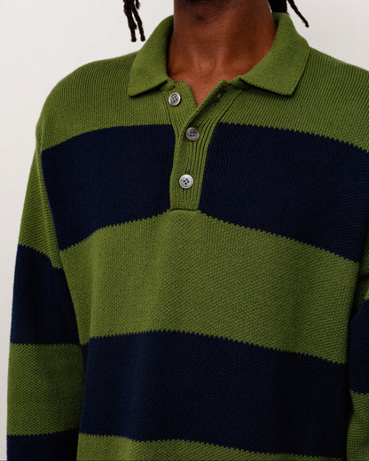 A close-up of a person wearing a ribbed knit polo sweater with horizontal olive green and navy blue stripes, featuring a three-button placket.