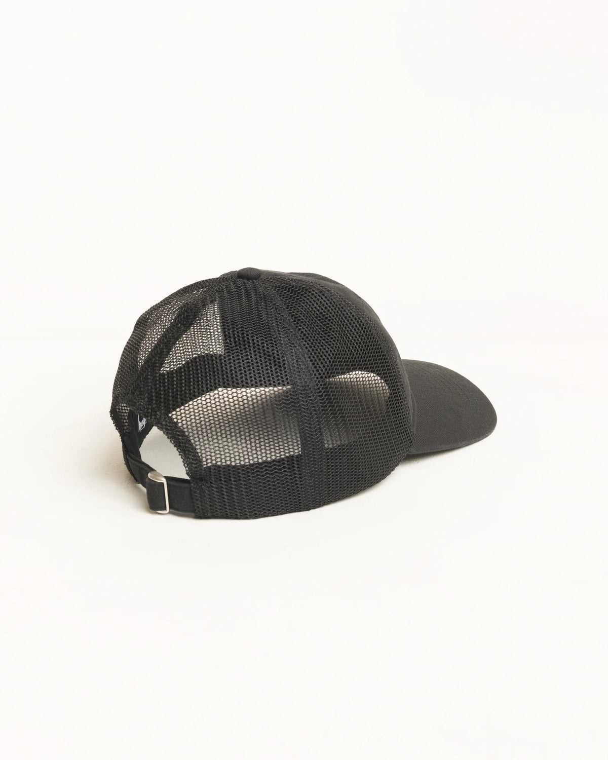 A black trucker-style cap with a black mesh back and solid black curved brim, photographed from the side against a clean white background.