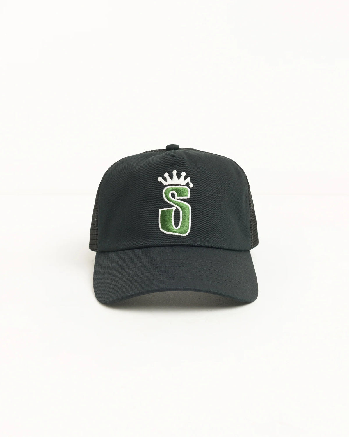 A black trucker-style baseball cap with a green and white embroidered letter 'S' under a small white crown on the front, shown against a plain white background.