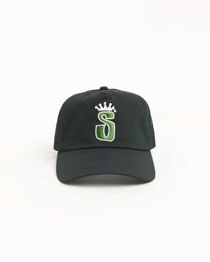 A black trucker-style baseball cap with a green and white embroidered letter 'S' under a small white crown on the front, shown against a plain white background.