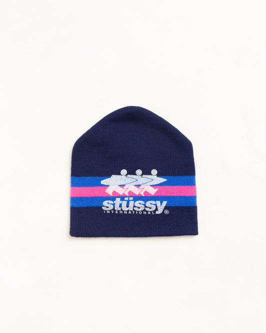 A navy blue knit beanie hat featuring a horizontal stripe design with pink and light blue bands, and the Stussy logo printed in white and blue across the center.