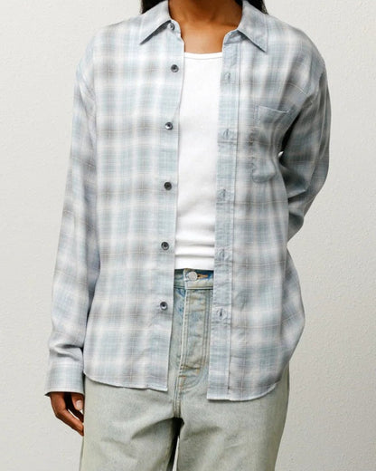 Person wearing a plaid shirt and light pants against a plain background