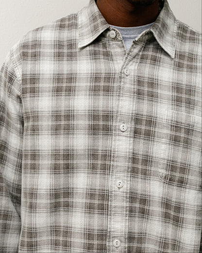 Person wearing a plaid shirt against a plain background