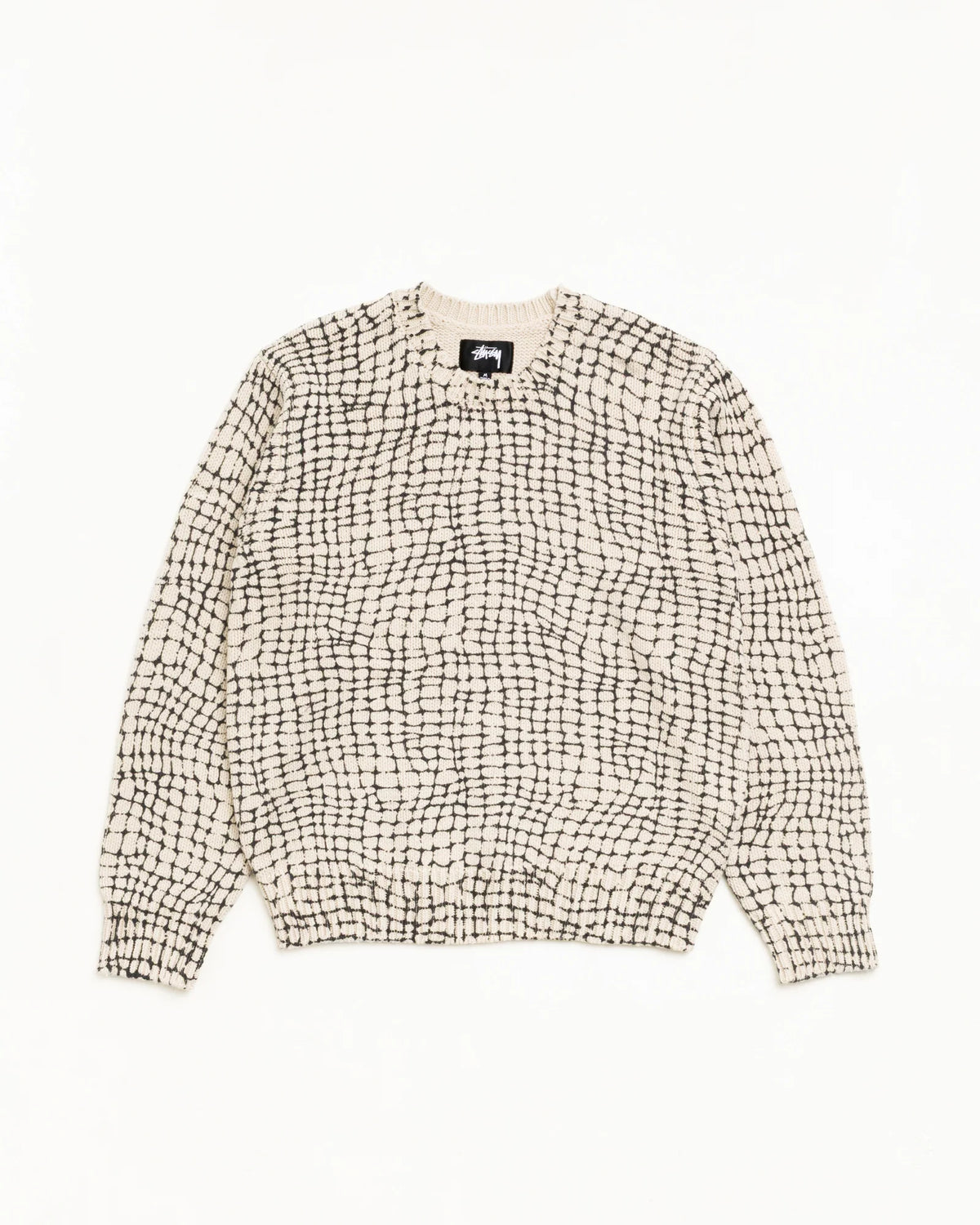 A cream-colored knit sweater with a black grid pattern, laid flat against a solid white background.