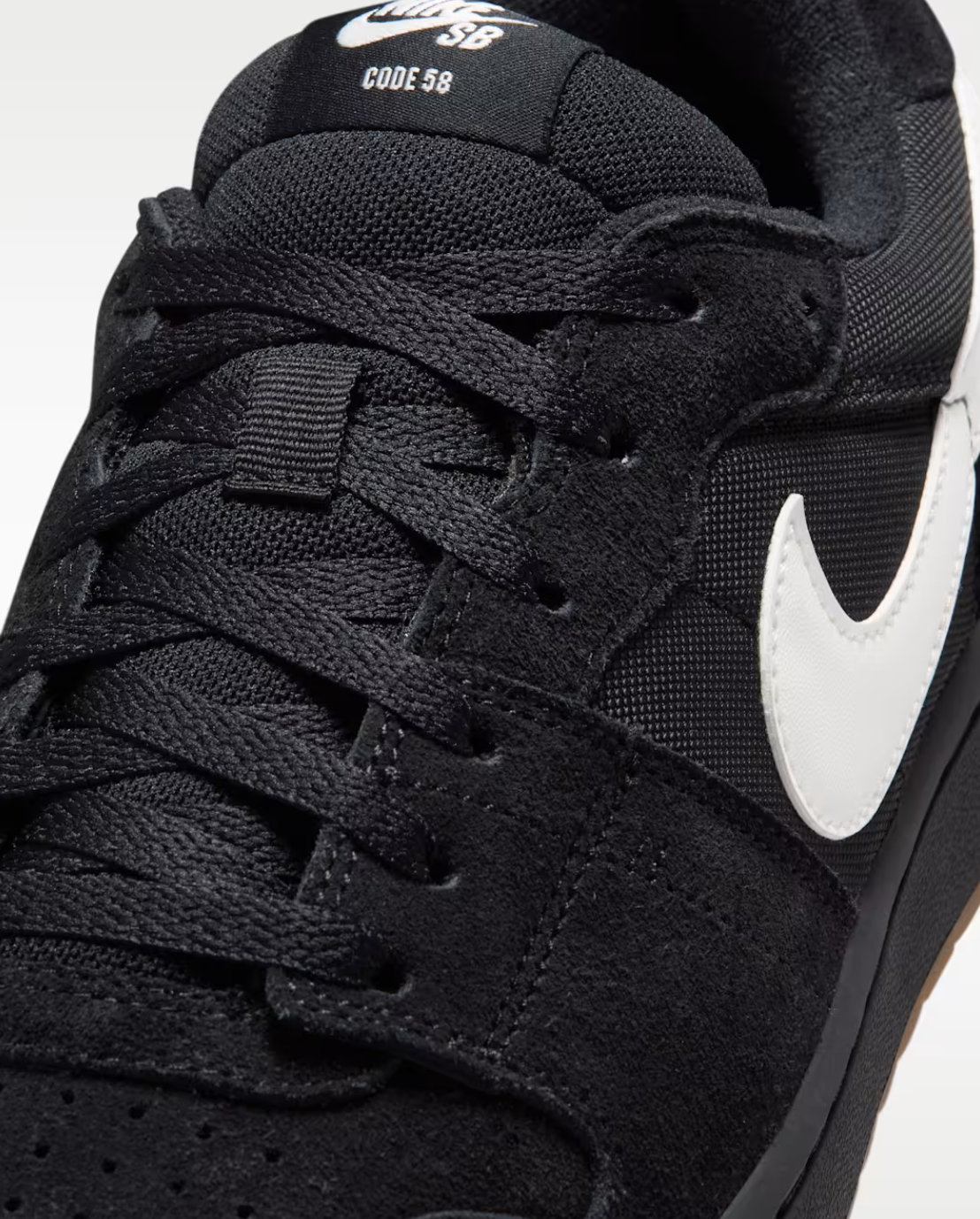 Close-up of a black Nike SB Code 98 sneaker showing the black textured upper, black laces, a white Nike Swoosh, and white 'SB CODE 98' text on the tongue.