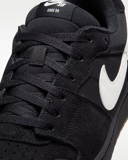 Close-up of a black Nike SB Code 98 sneaker showing the black textured upper, black laces, a white Nike Swoosh, and white 'SB CODE 98' text on the tongue.